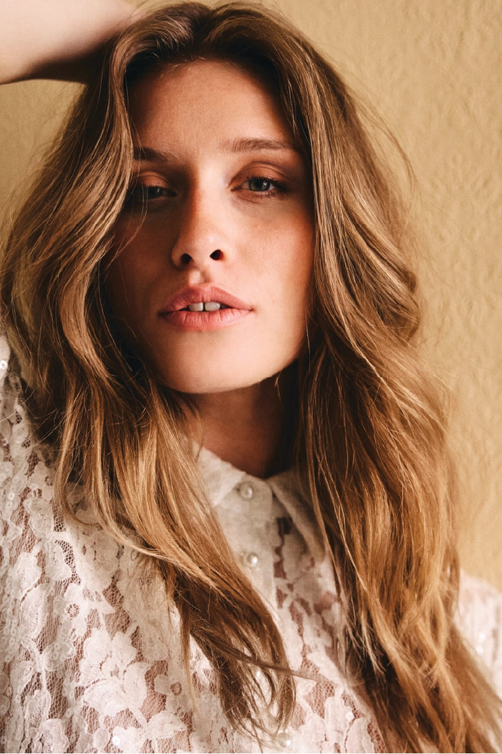 Kvinde i paliet blonde bluse, med sofistikeret blik